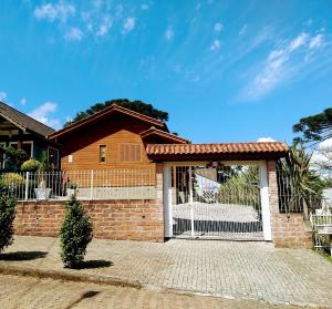 a house with a fence and a gate at Chalé Rosa in Canela