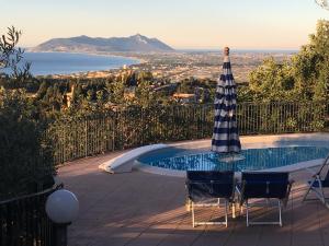 ein Pool mit Sonnenschirm und zwei Stühlen daneben in der Unterkunft Villa "Ai Galli" in Terracina