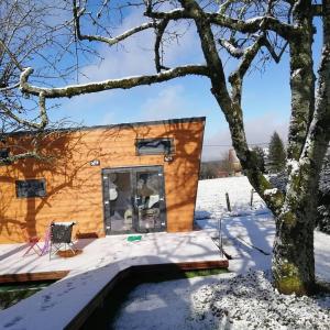 une cabane en rondins dans la neige avec un arbre dans l'établissement Ô p'tit nid Milie, à Bellefontaine