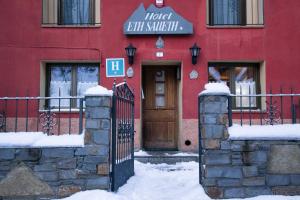 a red building with a gate and a hotel exit switch at Hotel Saueth in Tredós