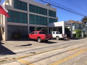 dos camiones estacionados en un estacionamiento frente a un edificio en Hotel Del Rio, en Constitución