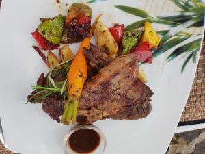 a plate of meat and vegetables with a tablespoon of sauce at Rockside Cabanas Hotel in Unawatuna