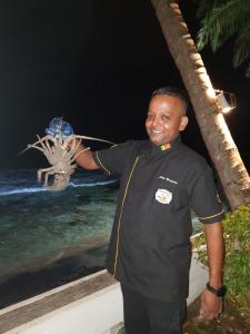 Un uomo in piedi vicino all'oceano di notte di Rockside Cabanas Hotel a Unawatuna