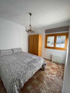 1 dormitorio con cama y lámpara de araña en Apartamentos Rurales Labrador, en Arbuniel