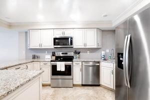 uma cozinha com armários brancos e um frigorífico de aço inoxidável em Beach Escape Condos em Daytona Beach Shores