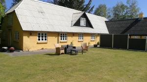 a yellow house with a table and chairs in the yard at Fædrelandet Ferielejlighed & Turridning in Læsø