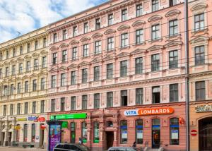 un grand bâtiment rose avec des voitures garées devant lui dans l'établissement You&Me7, à Riga