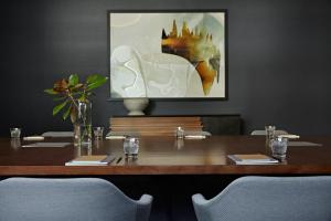 a wooden table with chairs and a painting on the wall at Kimpton Sawyer Hotel by IHG in Sacramento