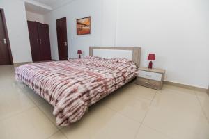 a bedroom with a bed with a blanket and a night stand at Appartement cosy à la plage - Pointe Noire in Pointe-Noire