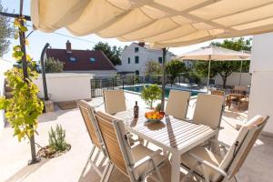 a table and chairs under an umbrella on a patio at VLATINO in Seget Vranjica
