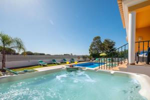 a swimming pool in a backyard with a patio with chairs at Villa Alegria in Albufeira