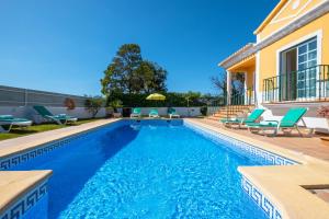 a swimming pool with chairs and a house at Villa Alegria in Albufeira