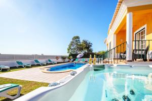 a swimming pool in a yard with chairs and a house at Villa Alegria in Albufeira