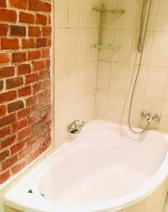 a bath tub with a shower and a brick wall at Lviv's Prospekt Shevchenka Apartments in Lviv