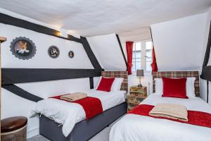 Dos camas en una habitación con rojo y blanco. en 5 Central Chambers, en Stratford-upon-Avon