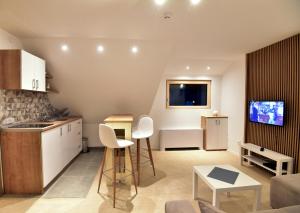 uma cozinha e sala de estar com armários brancos e uma televisão em Kopaonik konak Koznik em Kopaonik