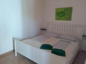 Una cama blanca en una habitación con una pintura verde en Finca Esmeralda, en Zahora