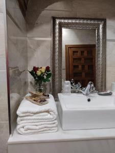 a bathroom with a sink and a mirror and towels at HABITACIONES LAS TERMAS in Guadix