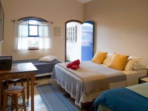 1 dormitorio con 2 camas, mesa y ventana en Sollar dos Gerânios, en Peruíbe