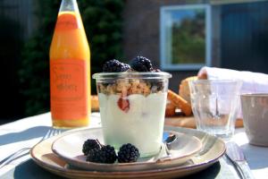 a jar of yogurt and berries on a plate with a drink at ZeeLand & Meer in Kamperland