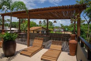 un patio con sillas de madera y pérgola en Recantos do Dende, en Itacaré