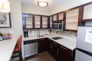 a kitchen with wooden cabinets and a white refrigerator at Staybridge Suites Bowling Green by IHG in Bowling Green