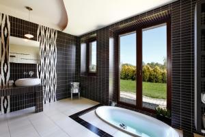 een badkamer met een bad en een groot raam bij Villa Port Rybaki in Szczuka
