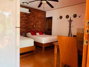a bedroom with two beds and a table and a ceiling fan at Casa de Descanso Lolha Bacalar in Bacalar