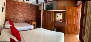 een slaapkamer met 2 bedden en een bakstenen muur bij Casa de descanso Bacalar in Bacalar