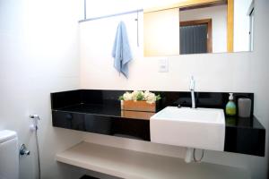 uma casa de banho com um lavatório branco e um espelho. em Apartamento Premium em Diamantina