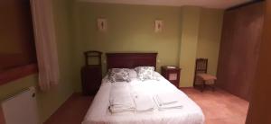 1 dormitorio con 1 cama con sábanas y almohadas blancas en Casa rural Las Mareas, en Casas del Monte