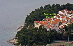 a house on top of a hill next to the water at Apartments Lavica Beach Dumičić in Podstrana