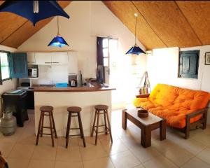 sala de estar con sofá naranja y cocina en Carpe Diem, en Aguas Dulces