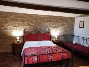 - une chambre avec un lit rouge et un mur en briques dans l'établissement Casale Belriguardo, à Ferrare