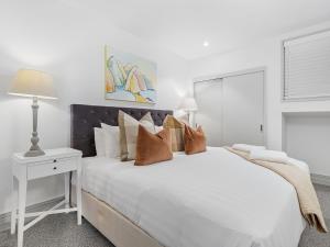 a white bedroom with a large white bed with pillows at Maison de Charme Central Apartment in Queenstown