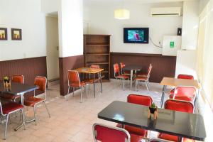 un restaurante con mesas y sillas y TV en la pared en Hotel Brisas en Villa Carlos Paz