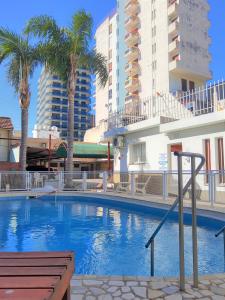 una gran piscina con palmeras y edificios en Hotel Brisas en Villa Carlos Paz