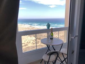 una mesa con una botella de vino en un balcón con vistas al océano en Apart. Playa La Barca en Costa Calma