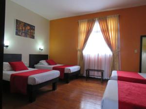 a hotel room with two beds and a window at Hotel La Herreria Colonial in Popayan