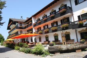 um hotel com bancos e guarda-sóis em frente em Farbinger Hof em Bernau am Chiemsee