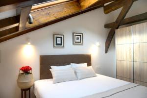a bedroom with a bed with white sheets and wooden ceilings at Casa Rural Andikoetxe Landetxea in Aulestia