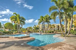 a swimming pool with palm trees in a resort at Aquatika Resort Condo with Private Beach Access! in Loiza