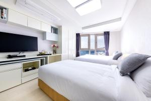 2 Betten in einem Zimmer mit einem TV und einem Bett sidx sidx sidx in der Unterkunft Shin Shin Hotel Seogwipo in Seogwipo