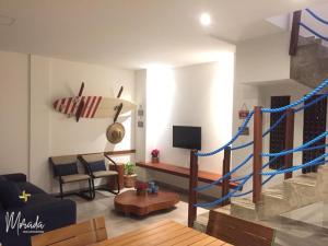 a living room with a staircase with a surfboard on the wall at Morada dos Cataventos (Frente Mar) in Barra de Camaratuba