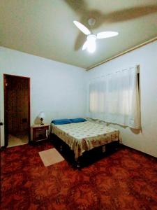 - une chambre avec un lit et un ventilateur de plafond dans l'établissement Casa para temporada em Cabo Frio, à Cabo Frio