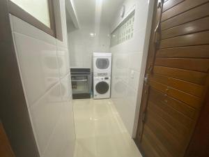 a small white kitchen with a washer and dryer at Casa Tropical pé na areia in Salvador