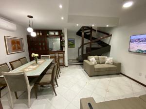 a dining room and living room with a table and chairs at Casa Tropical pé na areia in Salvador