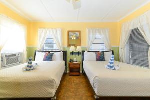 2 camas en una habitación con paredes y ventanas amarillas en The Palms Hotel en Cayo Hueso