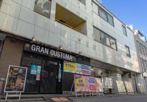 un magasin à l'avant d'un bâtiment avec des panneaux. dans l'établissement Gran Custama Ueno, à Tokyo