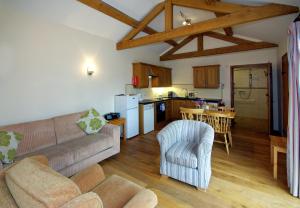 a living room with a couch and chairs and a kitchen at The Stables in Bromyard